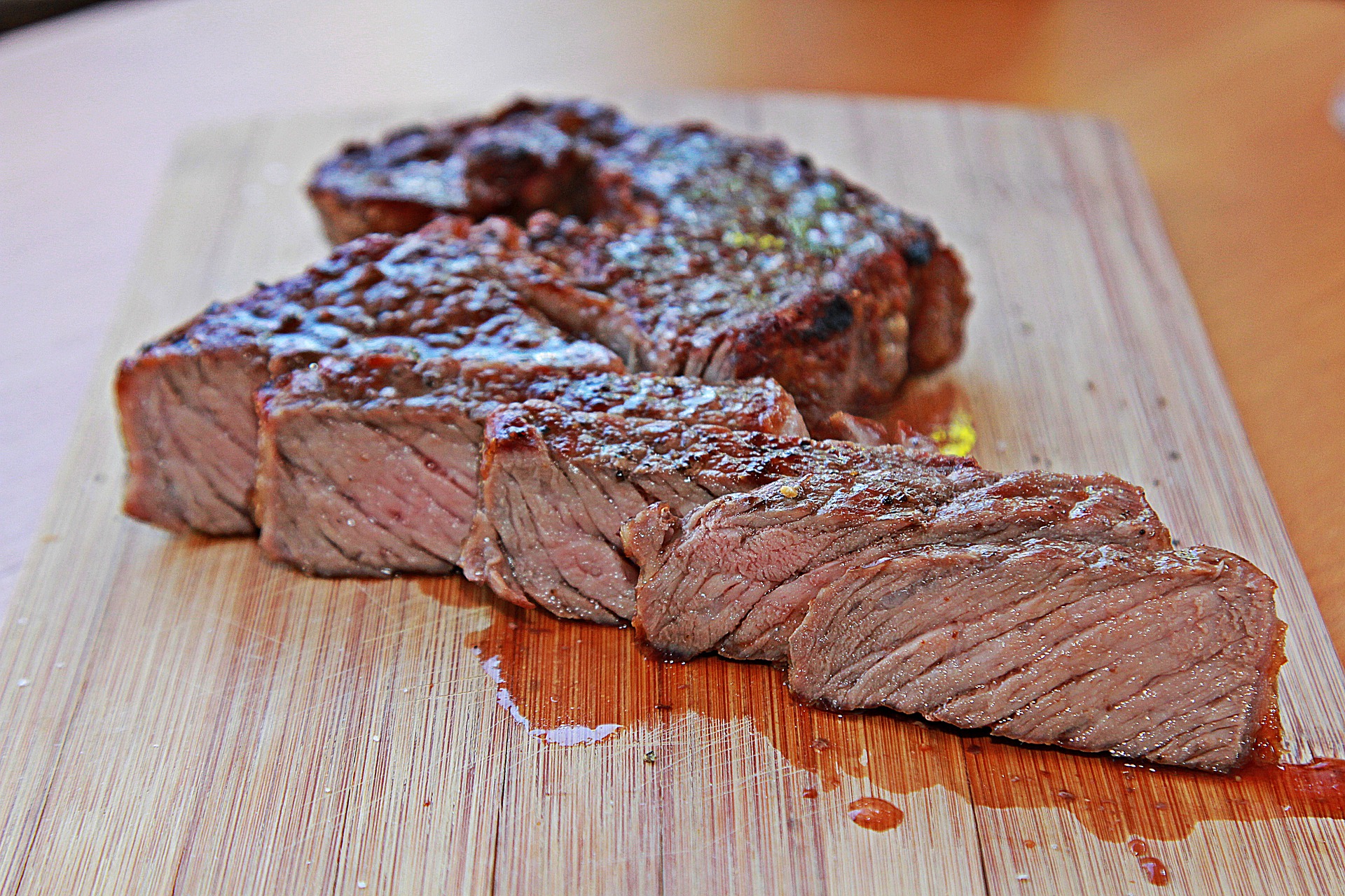 steak-4308529_1920 Juicy, grilled steak slices arranged on a wooden cutting board, showcasing a perfectly seared exterior and tender, pink interior, ideal for culinary enthusiasts and meat lovers.